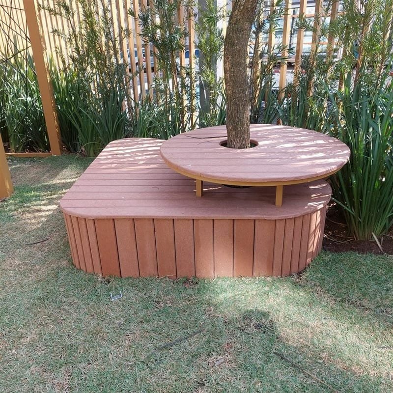Banco redondo em madeira ecológica ao redor de árvore em jardim de condomínio