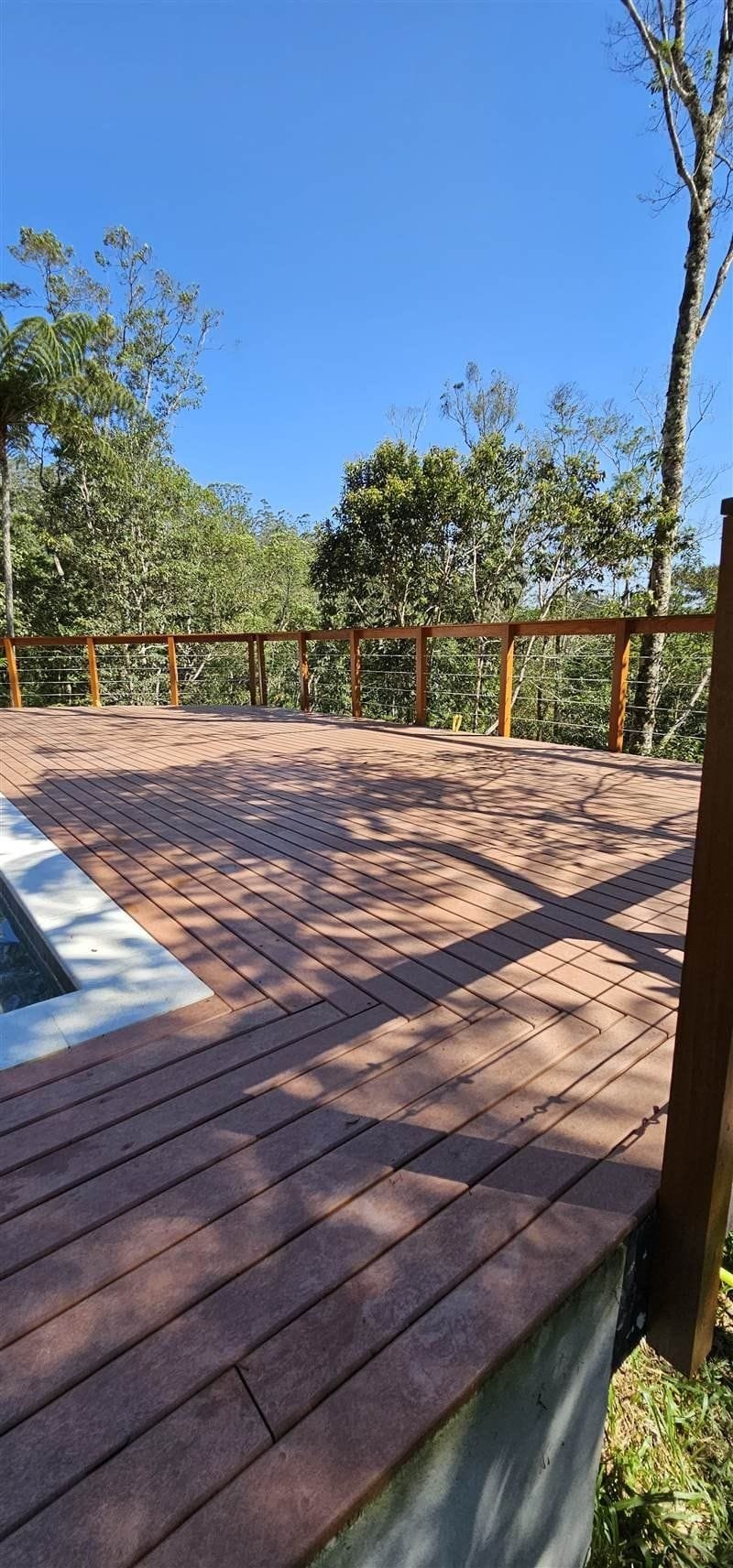 Deck curvo em madeira ecológica com guarda-corpo e vista para a mata, empreendimento de alto padrão