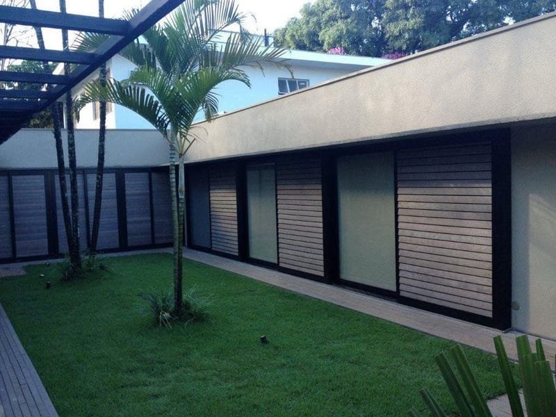 Fachada contemporânea com painéis de brise em madeira ecológica e jardim