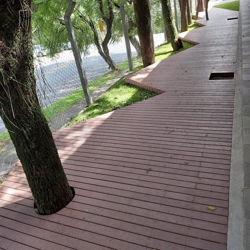 Passeio em deck de madeira ecológica entre árvores em jardim público