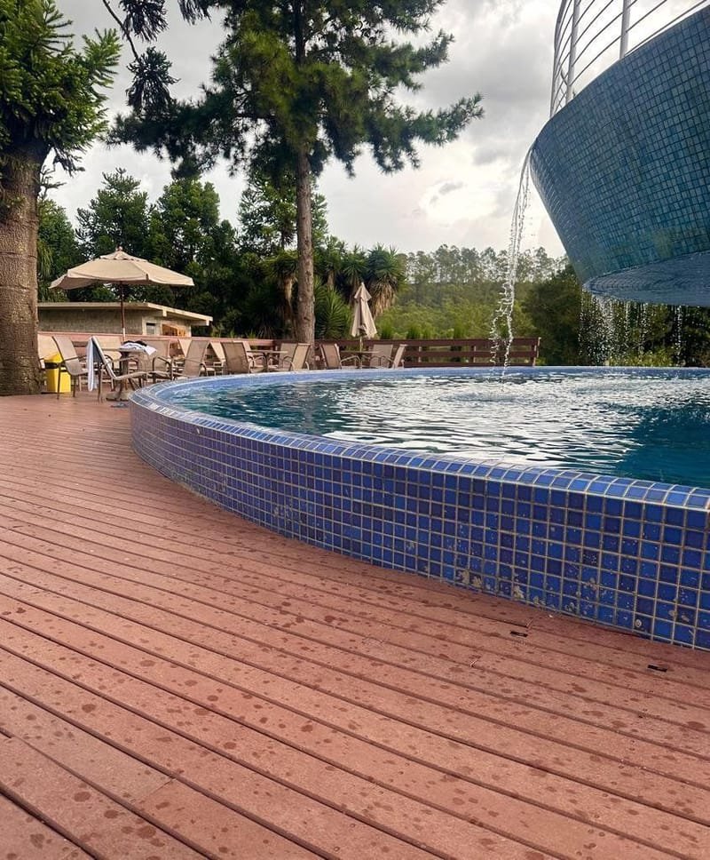 Deck curvo de madeira ecológica na borda de piscina de condomínio