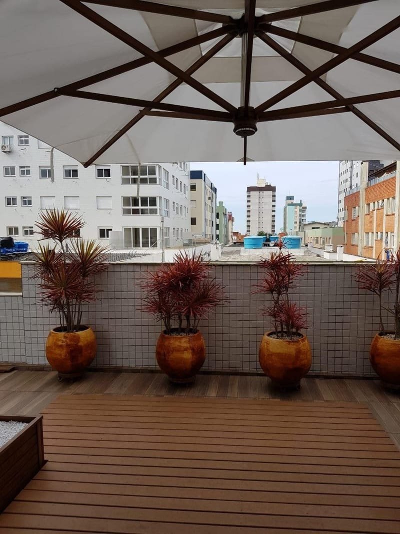 Terraço de cobertura de condomínio com deck de madeira ecológica, vasos e ombrelone
