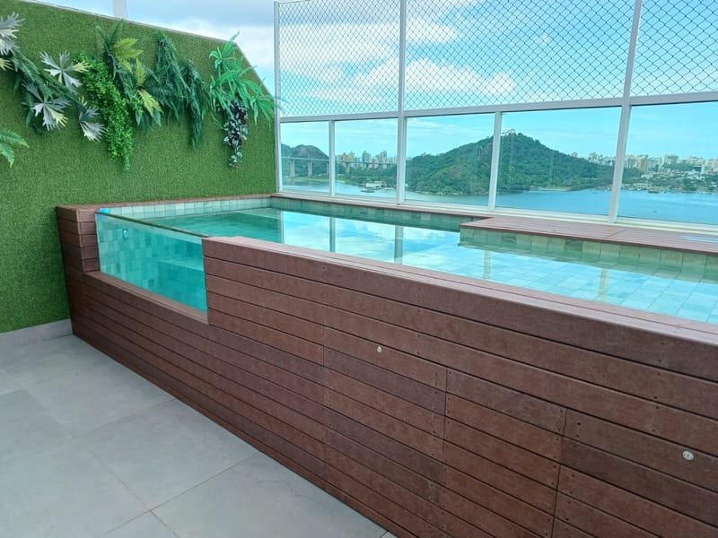 Piscina elevada com visor de vidro revestida em madeira ecológica maciça cor Marrom Café em cobertura com vista para o mar