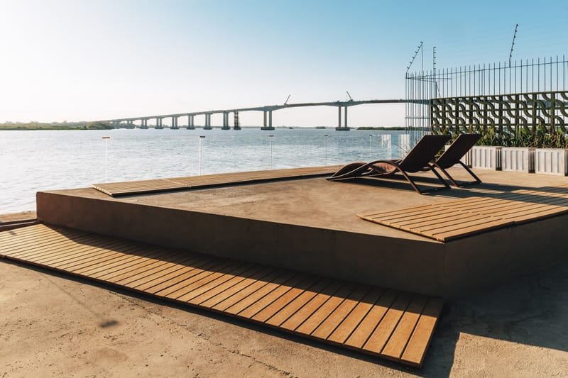 Deck em madeira ecológica maciça cor Teka com espreguiçadeiras em plataforma à beira d'água